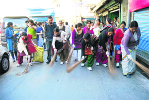 Women wielding brooms sweep the Mall Road near Kullri Bazaar in Mussoorie on Tuesday.