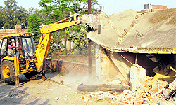 A JCB machine pulls down the front portion of shops on Pathankot Road in Jalandhar on Wednesday