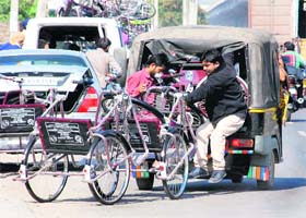 Beneficiaries hold wheelchairs while sitting inside a three-wheeler in Zirakpur on Thursday