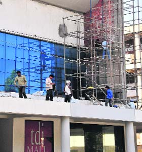 The tile work of the TDI Mall in Sector 17 being peeled off to give the facade a concrete finish