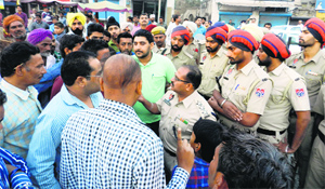 A police officer tries to convince the protesters to lift their traffic blockade at Khanna on Thursday.