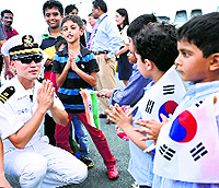 Children greet a naval officer after the arrival of Korean Navy Ships at the Port Trust in Chennai on Saturday.