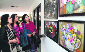 Women look at paintings at an art exhibition at Inderlok Hotel in Dehradun on Sunday.