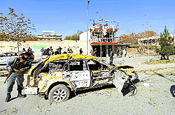 Afghan policemen stand at the site of a blast in Kabul on Sunday