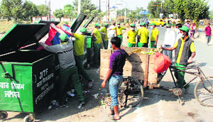 Workers of a private company at a garbage dump site in Jalandhar on Monday. 