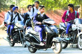 Government school students ride two-wheelers without helmet in Chandigarh on Tuesday