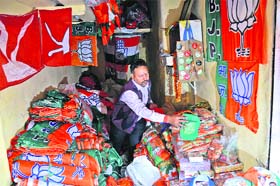 A shopkeeper display flags, banners and symbols of various political parties in Jammu