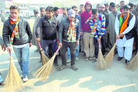 BJP supporters pick up brooms to clean a road in Kangan