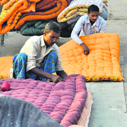 Quilt makers busy in work ahead of winters alongside a road in Patiala on Wednesday.