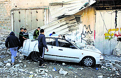 Palestinians stand next to a car damaged during the demolition of a house in East Jerusalem on Wednesday