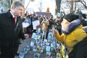 Ukraines President Petro Poroshenko talks with a woman during a wreath laying ceremony at the monument to the fallen Heroes in Kiev on Friday.