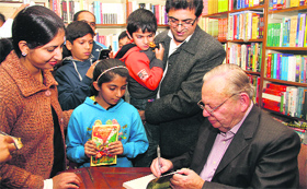 Author Ruskin Bond signs a copy of his book With Love From Hills for visitors at Green Book Shop in Dehradun on Saturday.