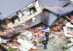 an aerial view shows rescue workers investigating collapsed houses after an earthquake in Hakuba town, Japan, on Sunday
