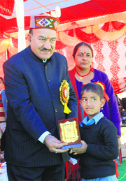 Health and Revenue Minister Kaul Singh gives a prize to a student at Government Senior Secondary School, Balu, in Mandi on Monday.
