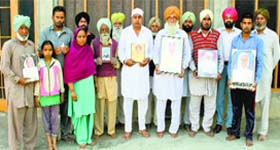 Family members show pictures of their kin who died of cancer at Mari Mustafa village of Moga district, on Monday