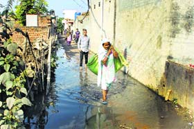 Residents of Ganna village in Phillaur wade through a street flooded with sewage on Sunday
