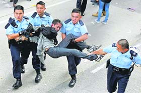 A pro-democracy protester is taken away by police officers as workers start clearing away barricades in Mong Kok on Tuesday