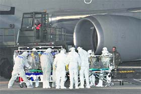 Italian doctors carry an Ebola patient to an ambulance after a Boeing KC-767 of the Italian Air Force landed near Rome