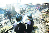 Firemen douse flames at a slum in Mumbai on Thursday