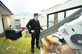 A man surveys the damage in his roofless apartment in Brisbane, Australia, on Friday