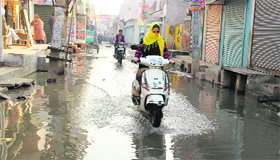 A commuter wades through a waterlogged road at Partap Nagar in Bathinda on Sunday.