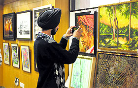 A visitor takes a picture of a painting at the TAC Art Gallery in Ludhiana. 